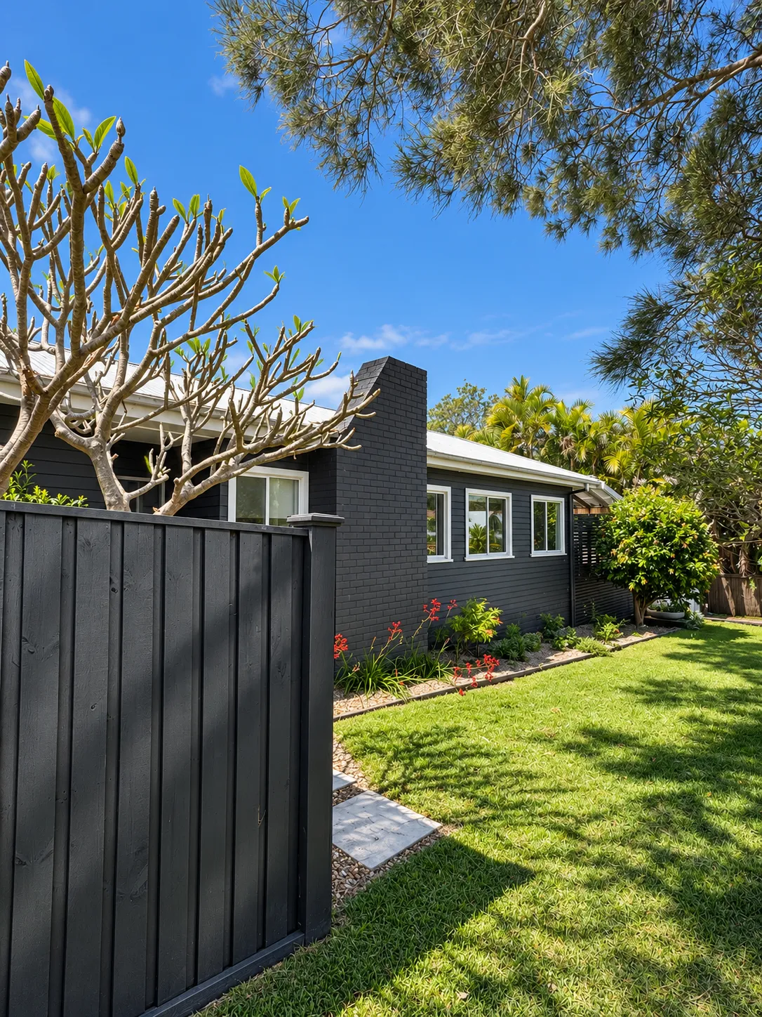 Black timber fence curving along the lawn towards the cottage