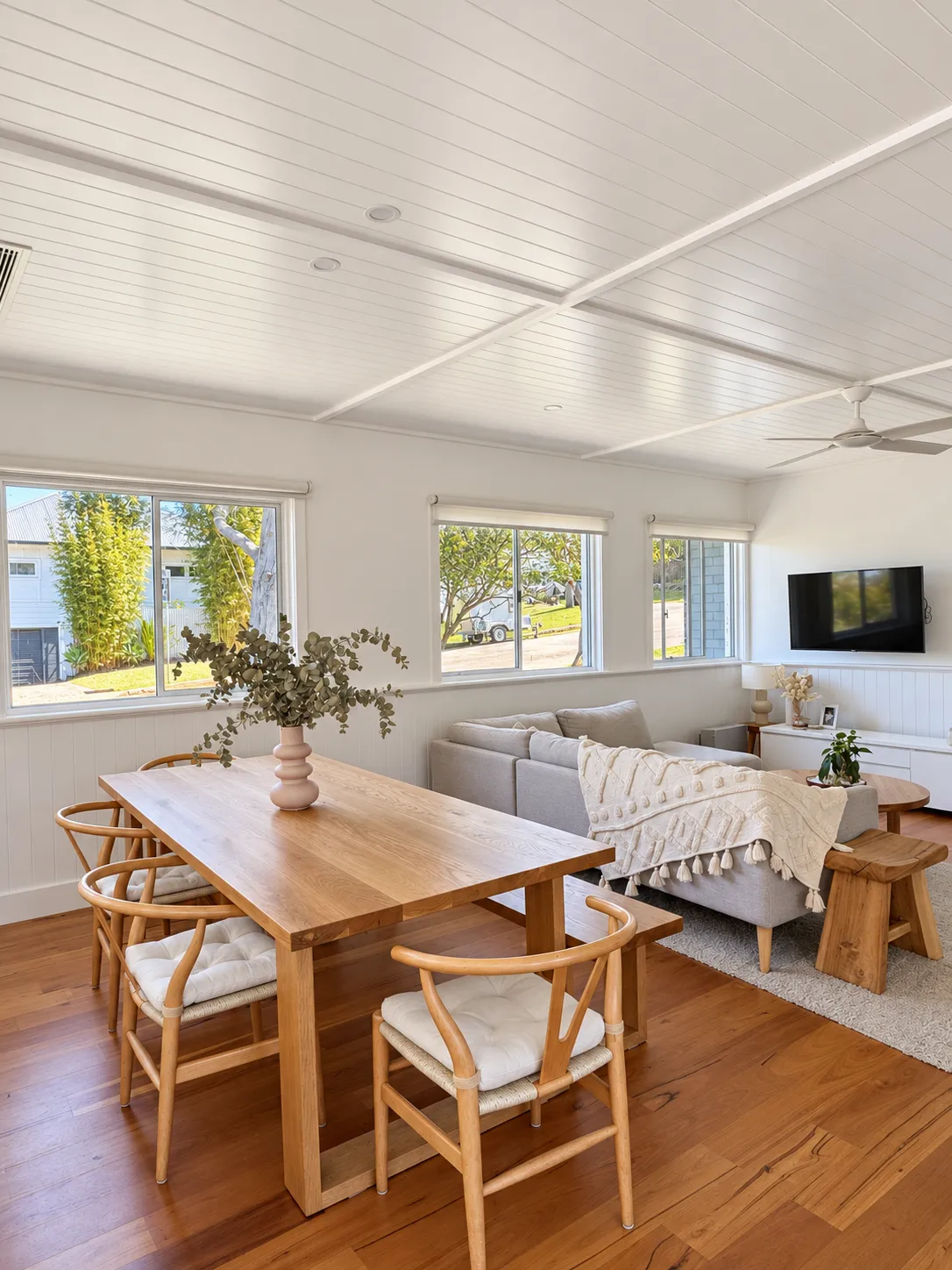 Dining table and sofa under a white lined ceiling