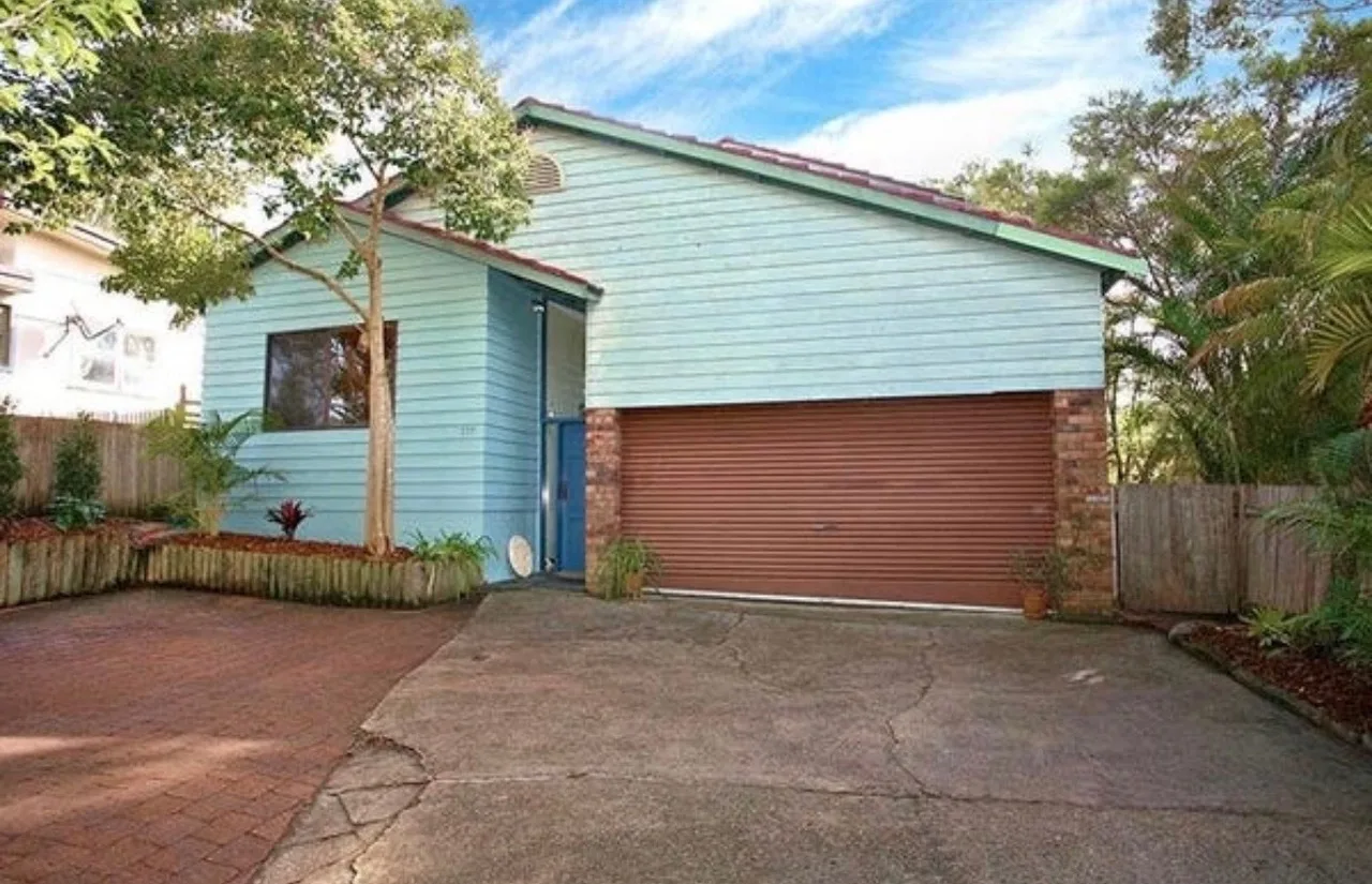 Front of the Avalon house before the renovation: pale blue weatherboard with a brown roller door