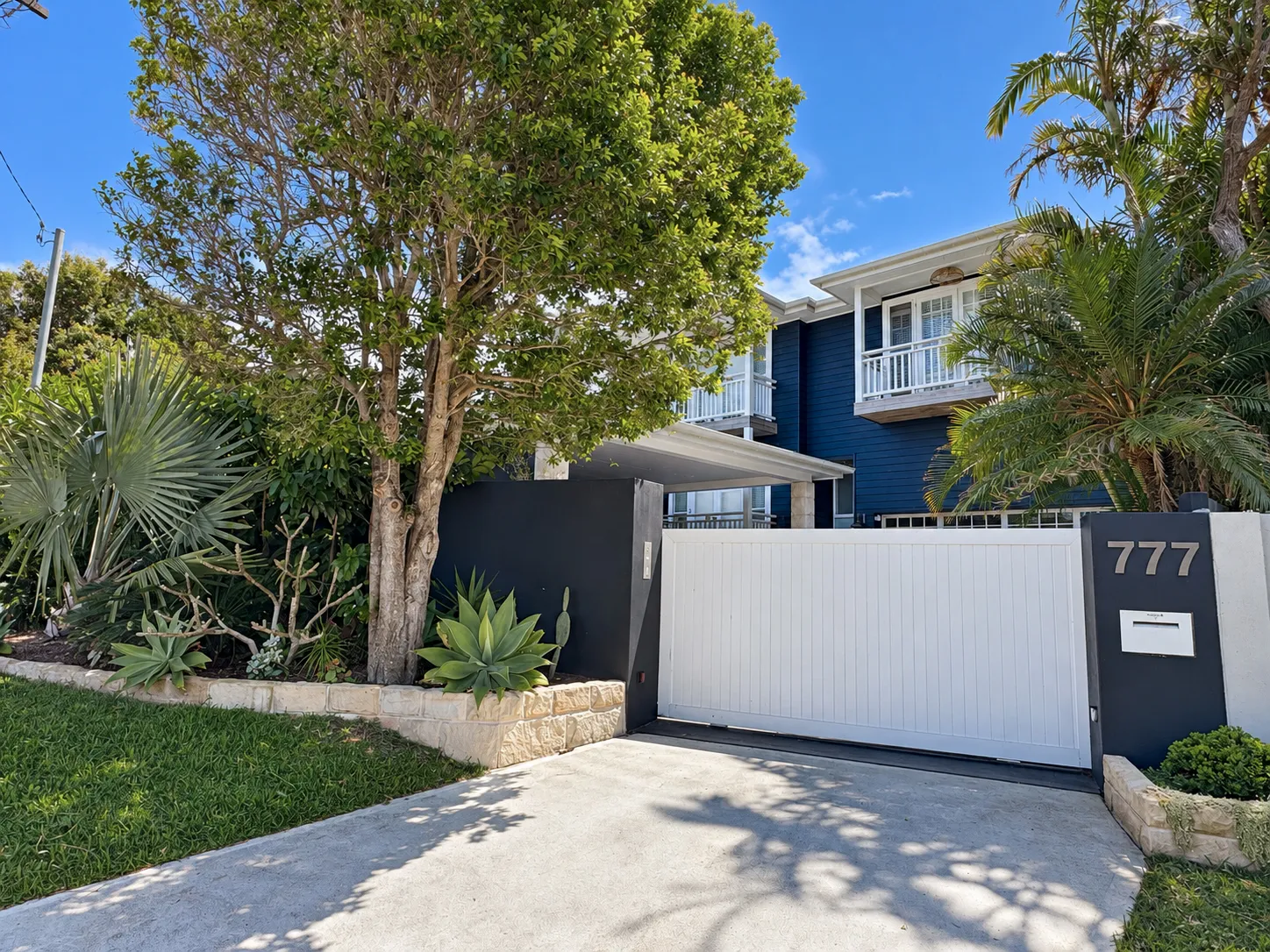 Driveway gate and landscaping in front of the black house