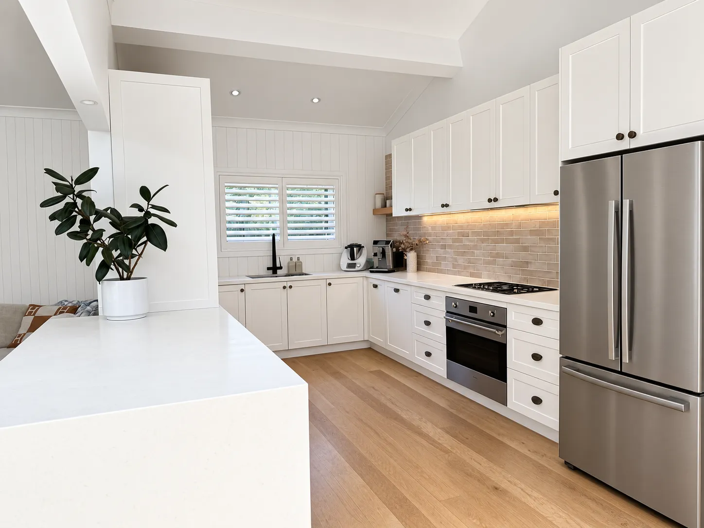 White shaker kitchen with timber floor and stainless steel fridge