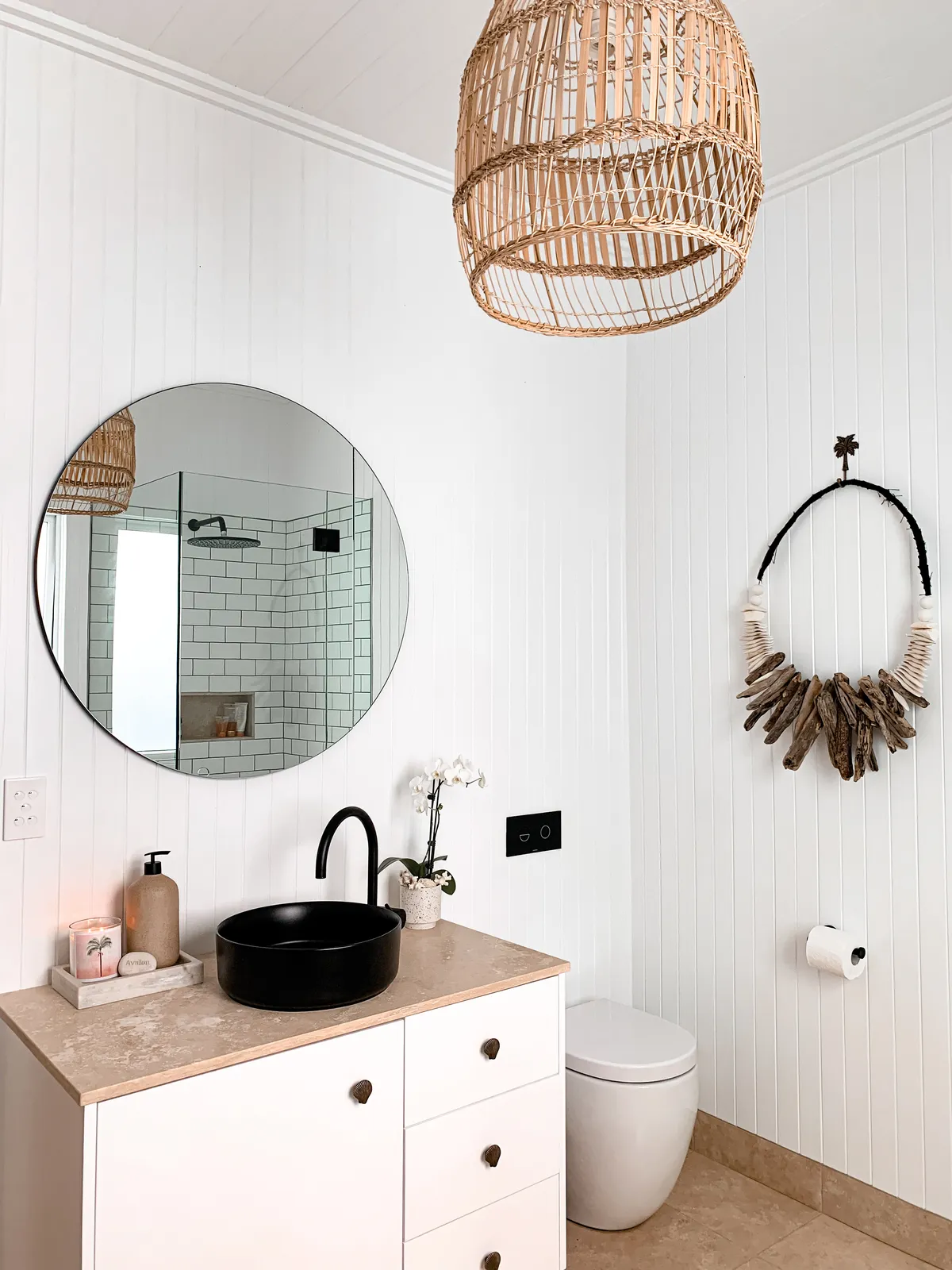 Powder room with black basin, round mirror and cane pendant