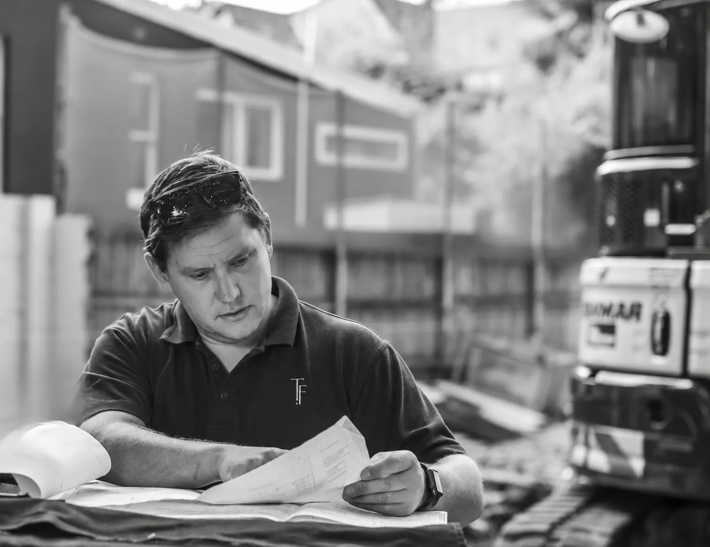 Chris Heath reviewing building plans on site, wearing a Trueform shirt