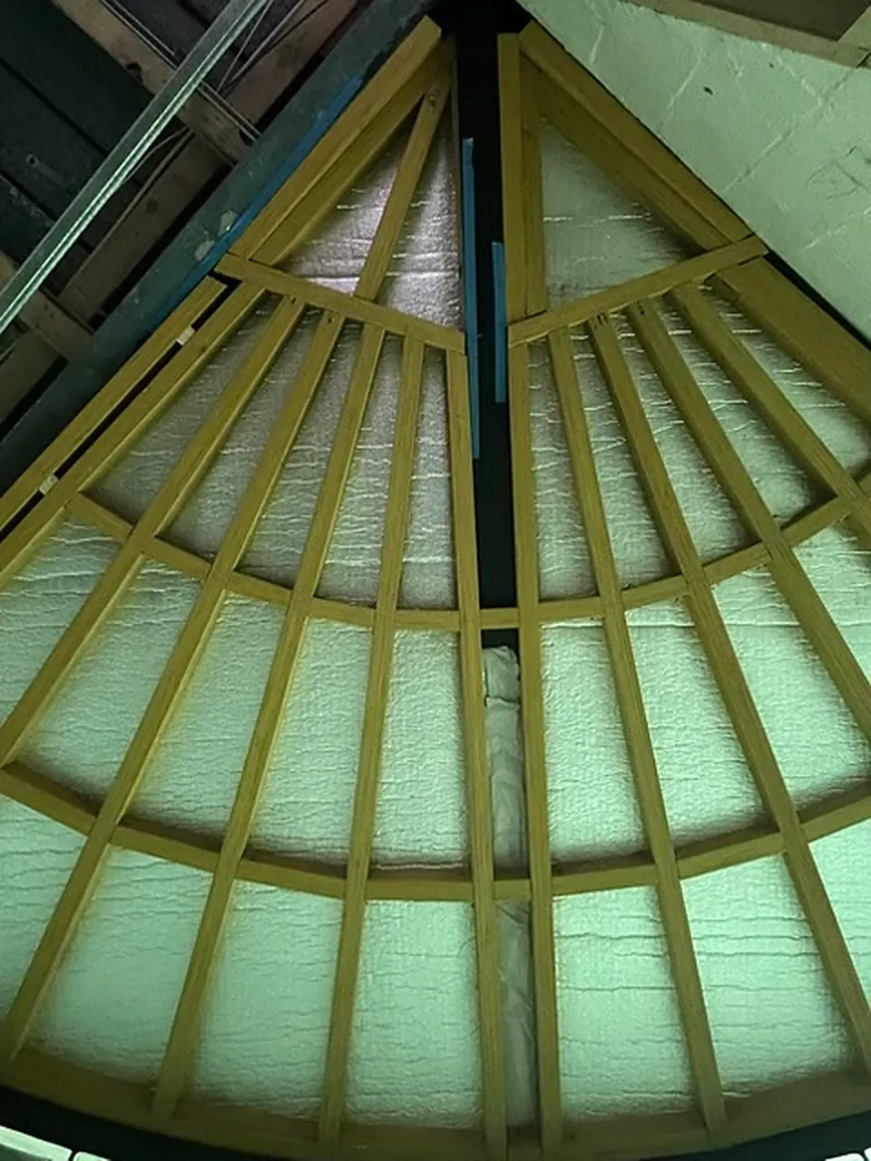 Looking up at curved roof rafters fanning out from a central ridge