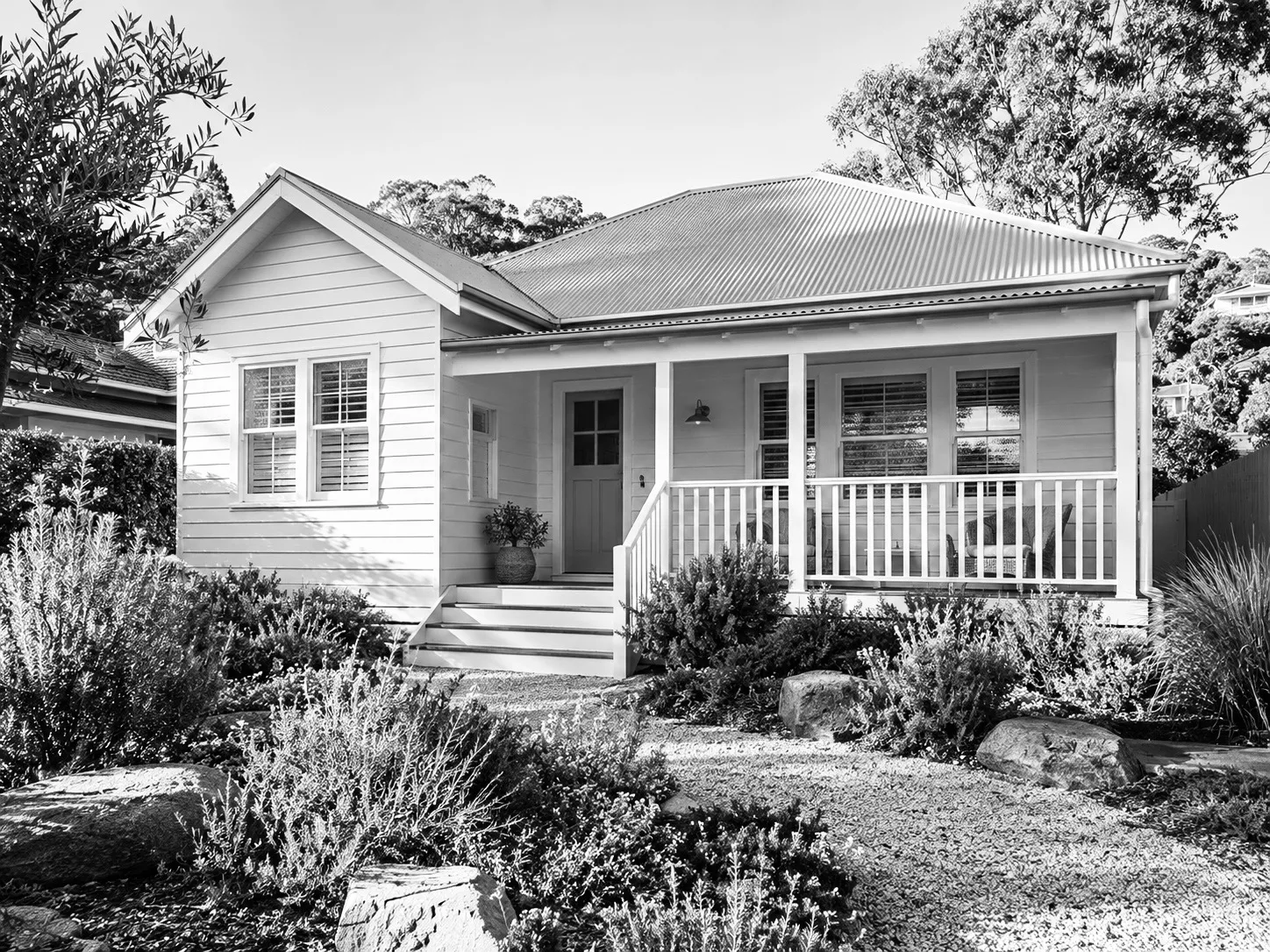 Weatherboard cottage with front verandah and garden, black and white
