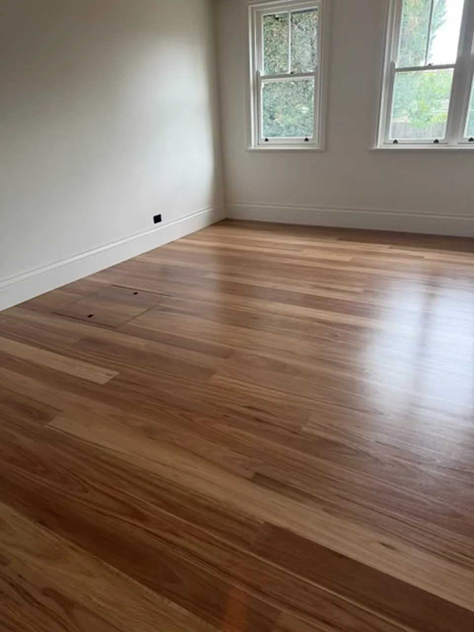 Empty room with freshly finished spotted gum floorboards and white walls